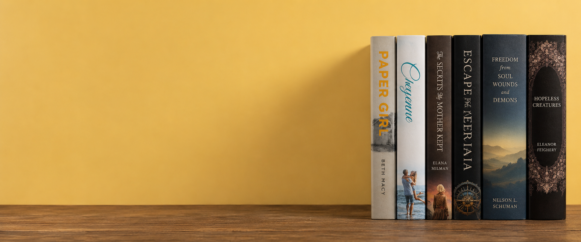 A row of hardback books resting against a warm yellow wall